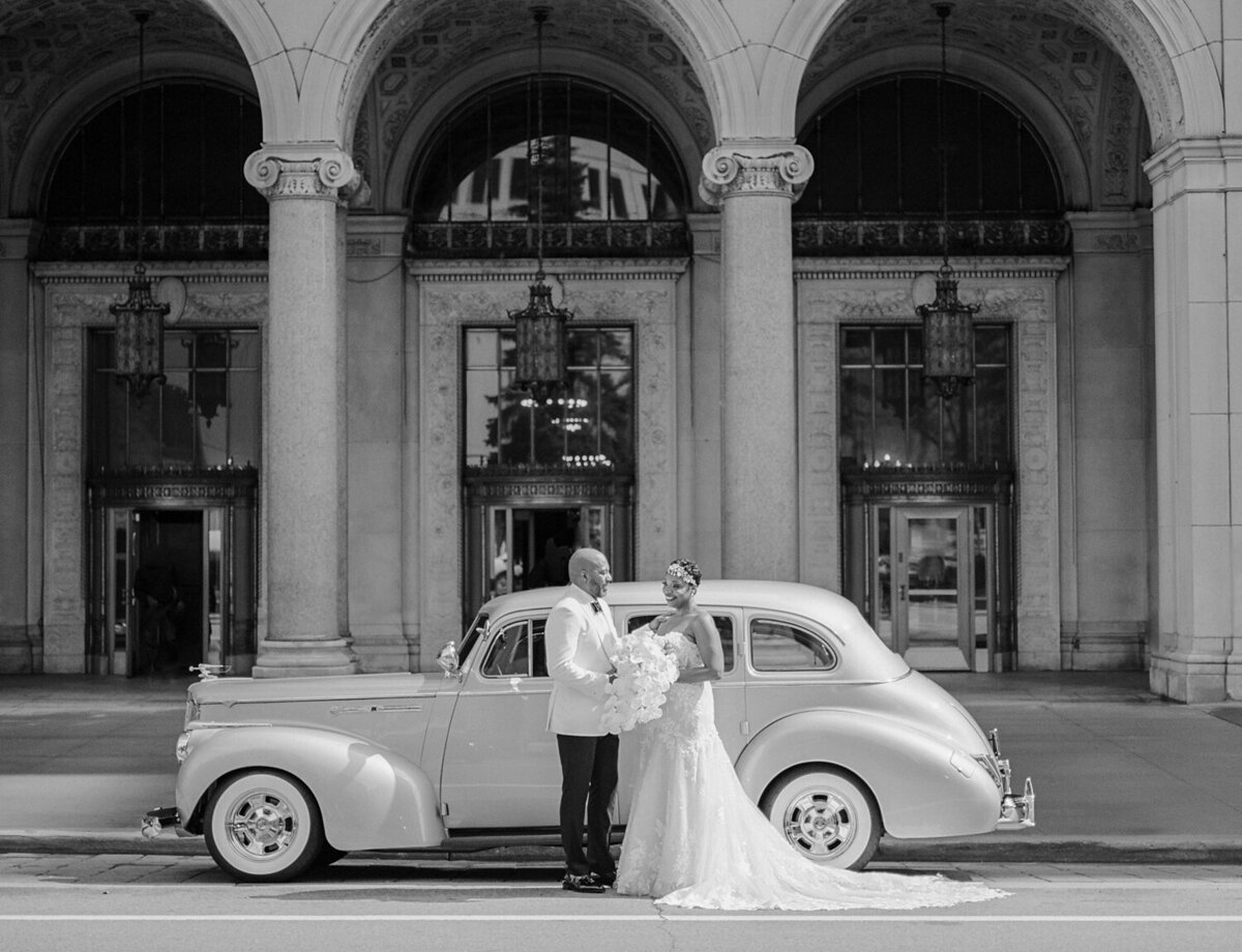 black wedding couple with vintage wedding car and ornate Detroit architecture, Michigan wedding photographer Christina Harrison