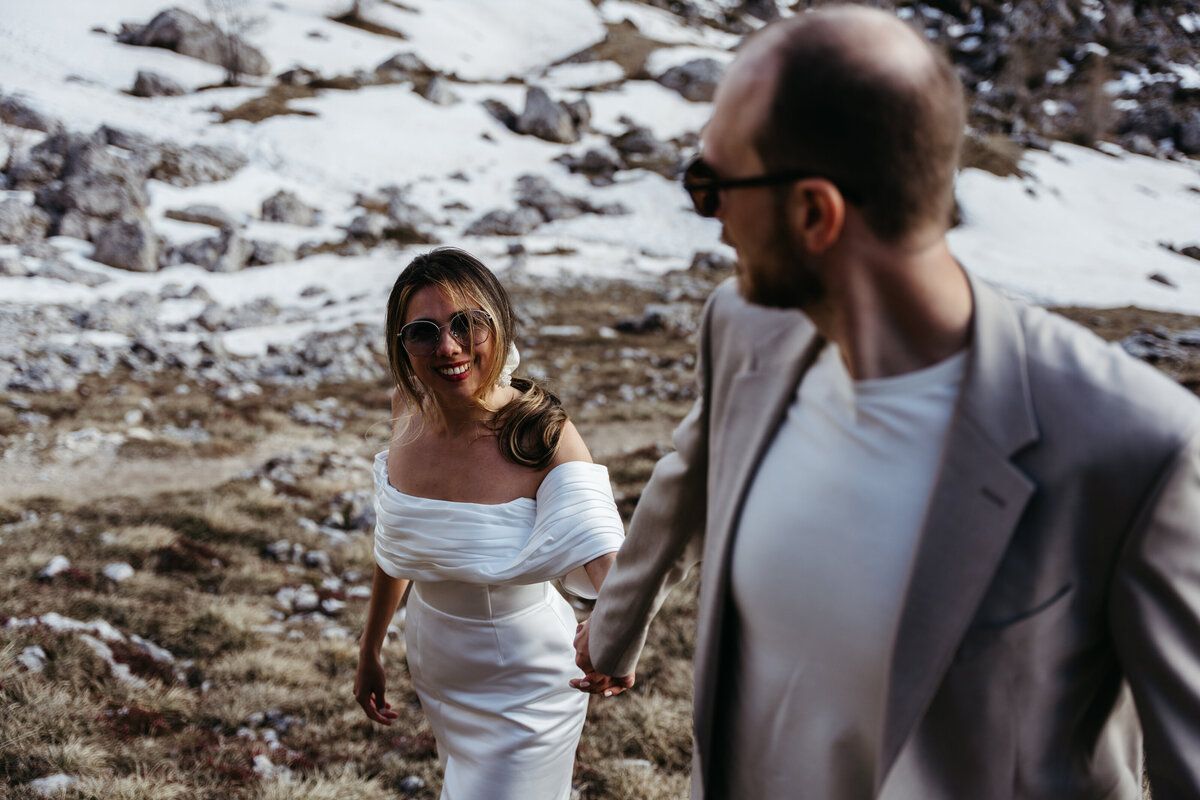 Bride and groom hiking together along mountain ridge