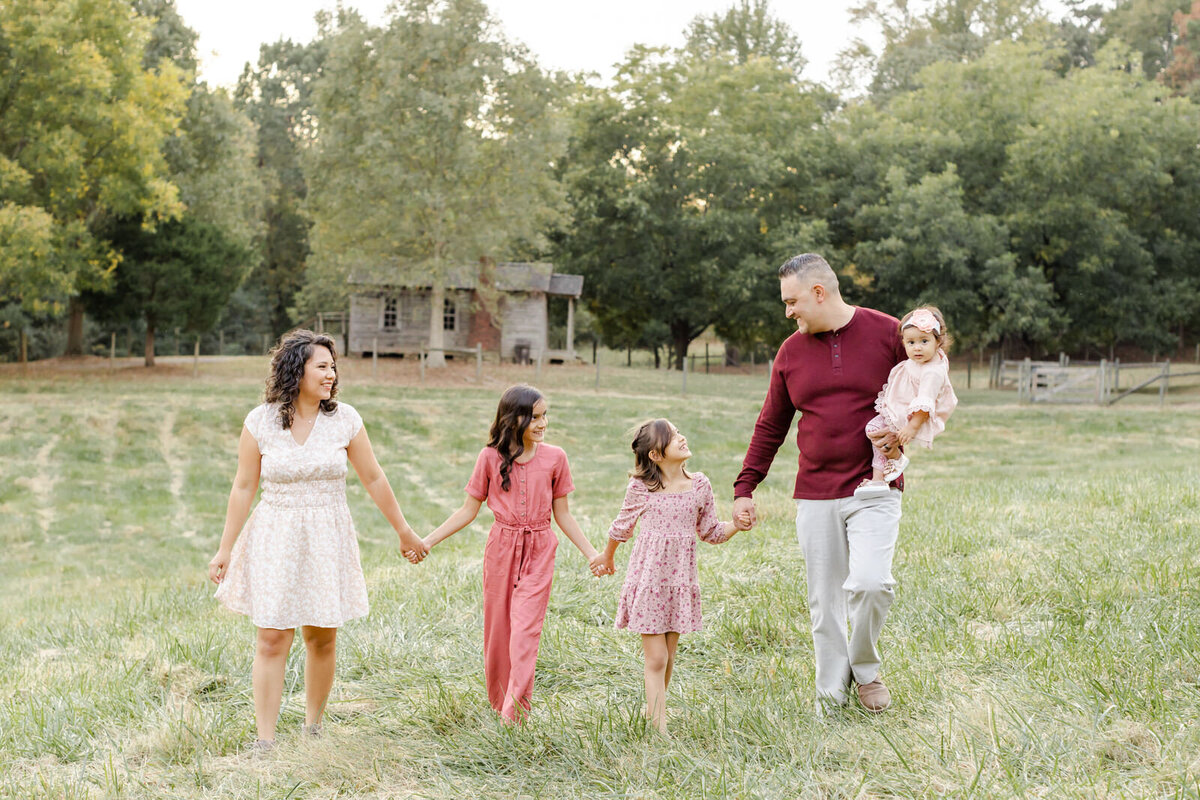 A family of 5 walk holding hands and smile at each other during a family mini-session in Duluth