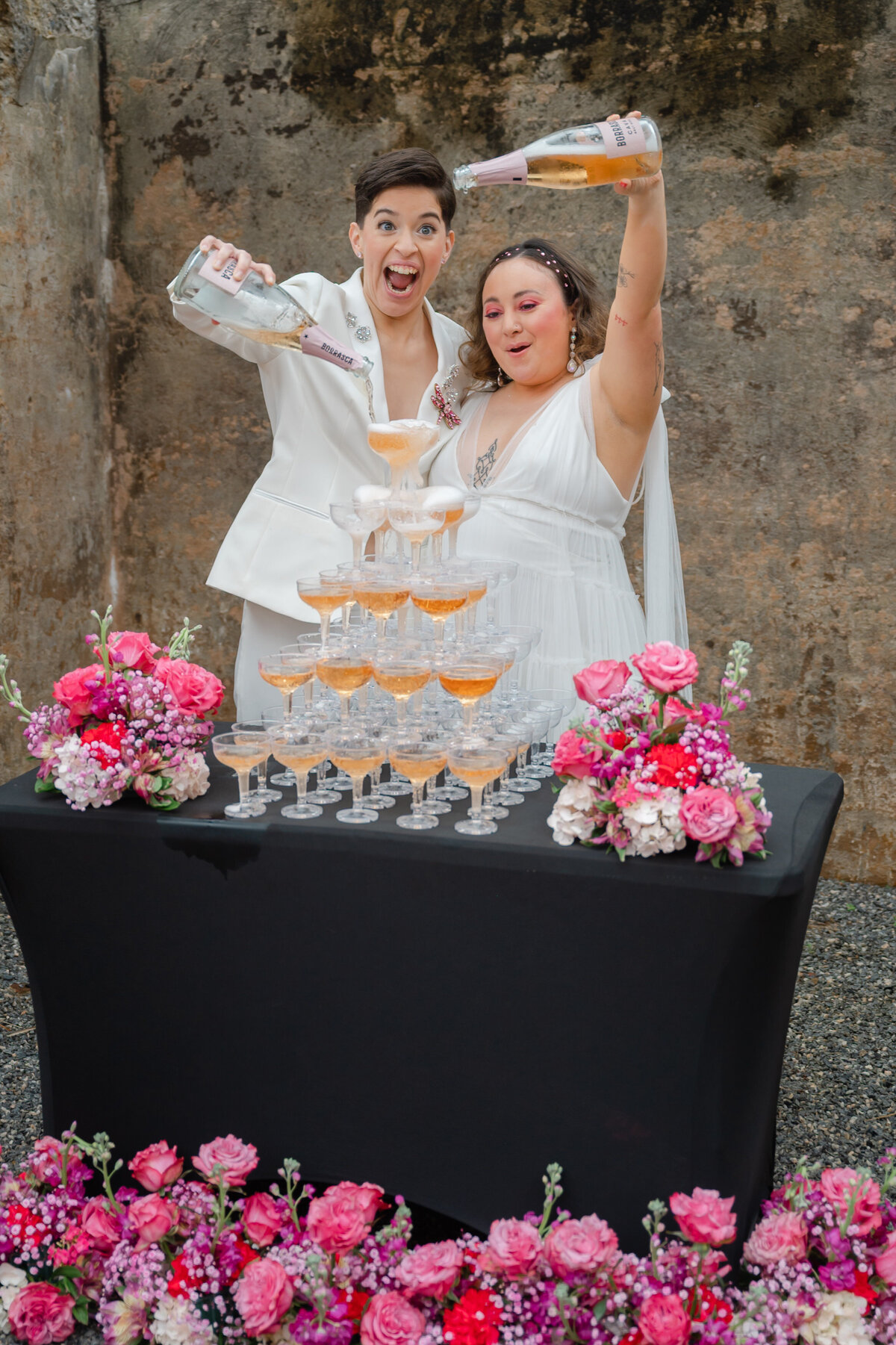 Two brides pouring champagne in champagne tower