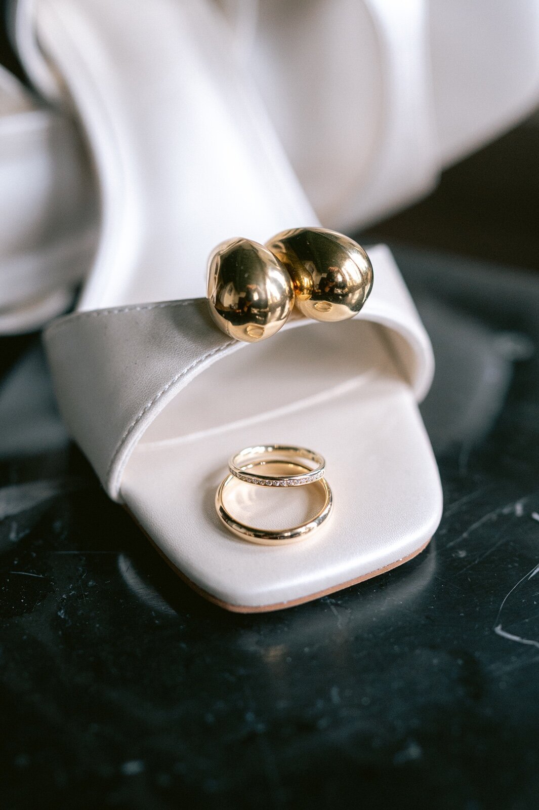Detailshot van trouwschoenen, oorbellen en trouwringen