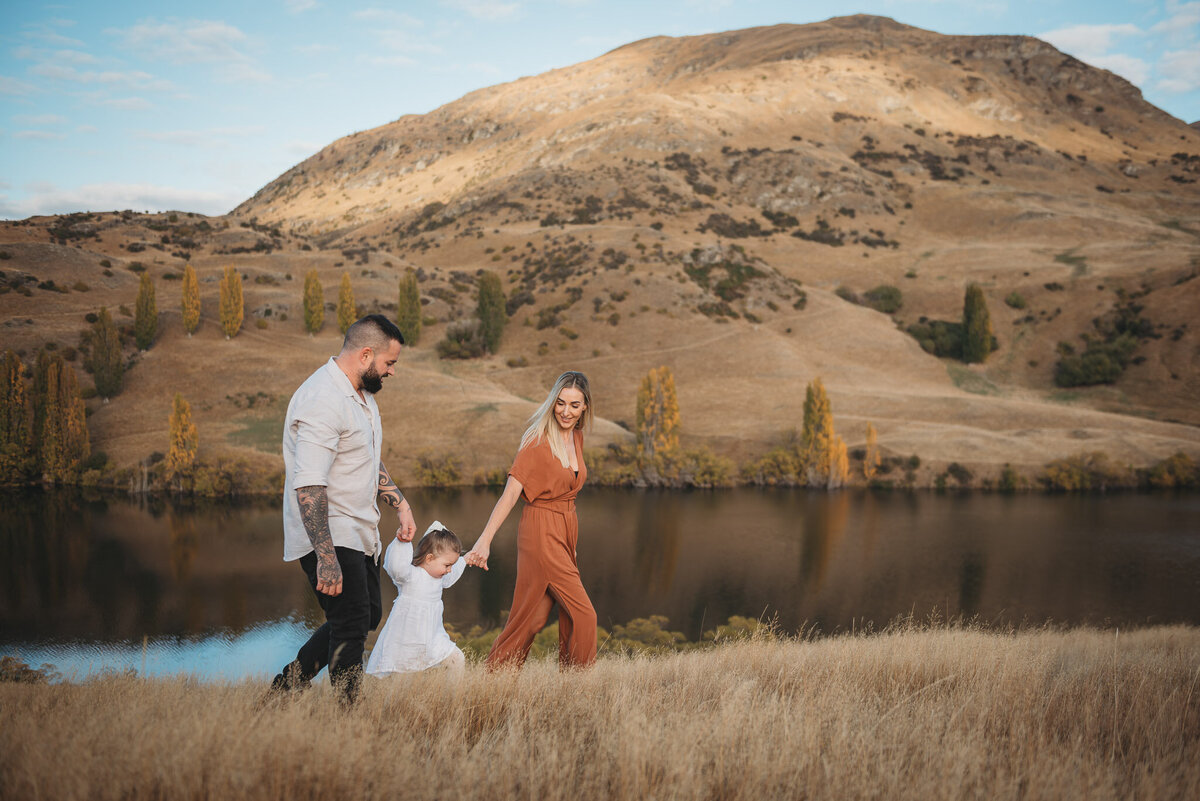 a family walking in the grass during their queenstown family photography session captured by Bie