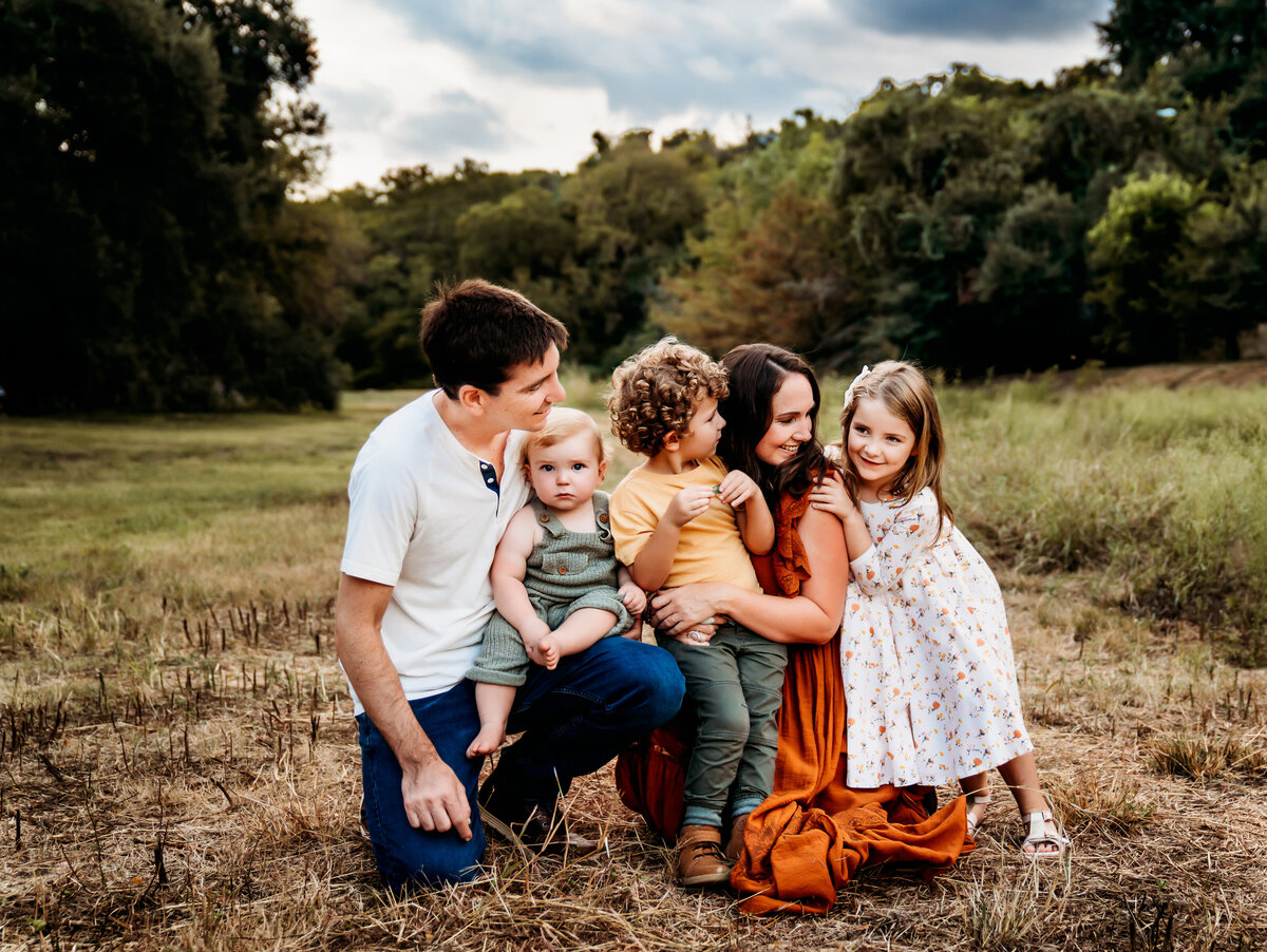 Family Photographer, a family of five kneels in a meadow among trees