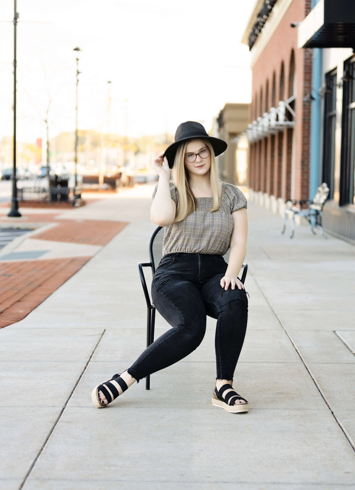 Senior photo of girl posing on a chair on the sidewalk of the West Erie Plaza in Erie Pa