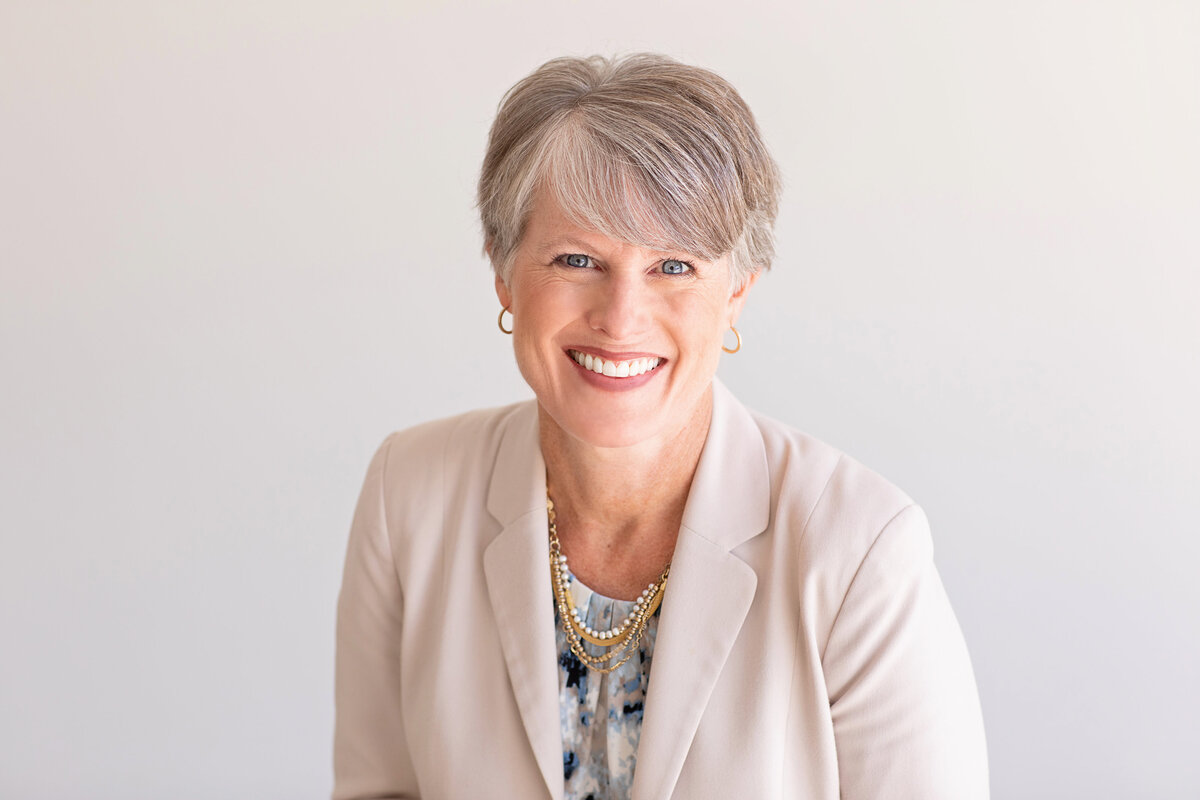 Woman in business attire smiling warmly for a corporate headshot