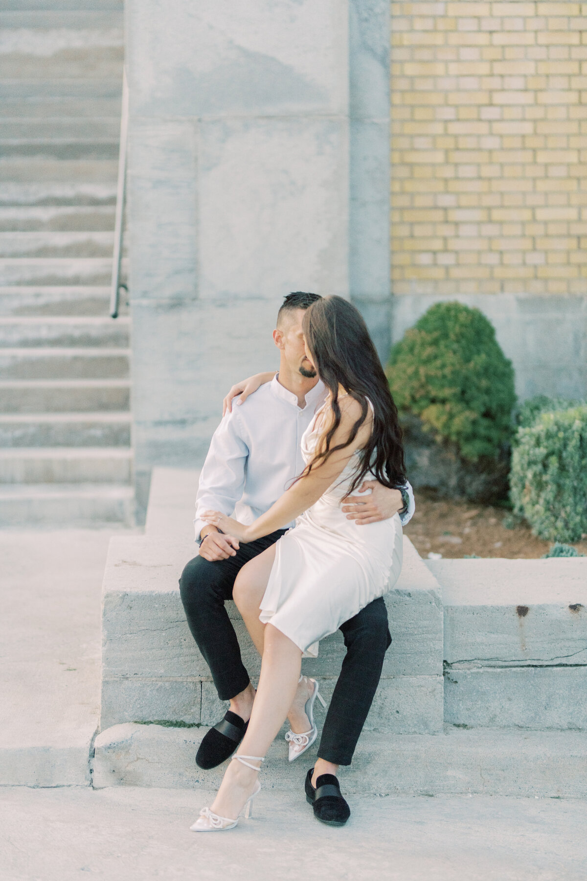 Couple sharing a joyful kiss, lost in a moment of pure love and happiness against the stone walls of Toronto’s RC Harris Water Treatment Plant