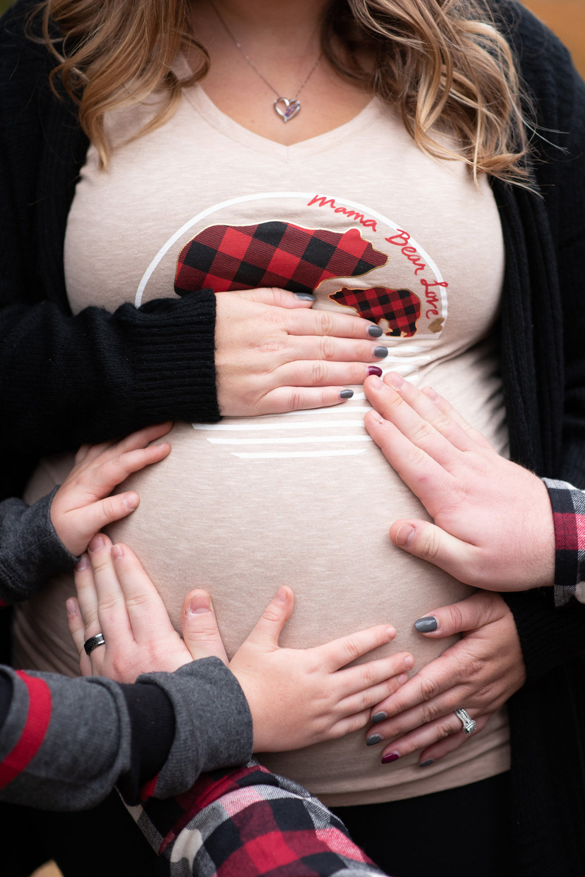 Mom Dad and brother's hands on Mom's pregnant belly