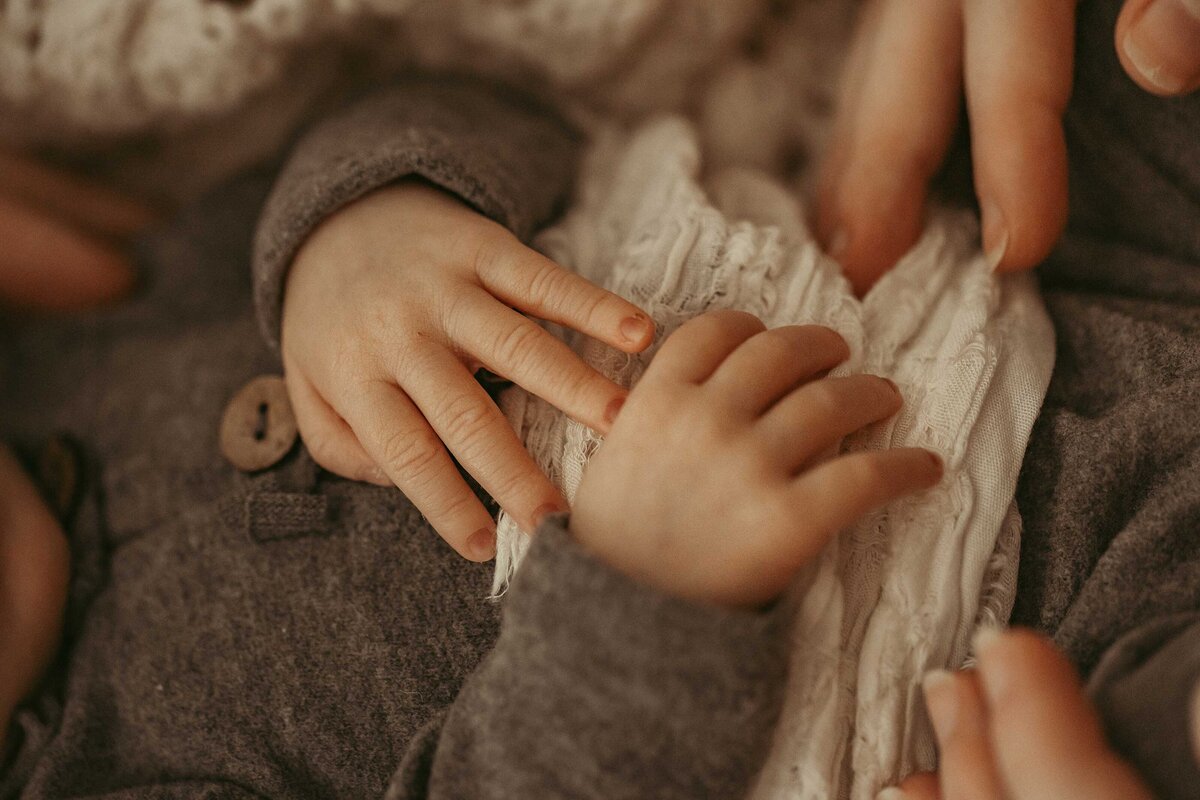 newborn baby hands close up. The baby is wearing a soft heather  gray outfit