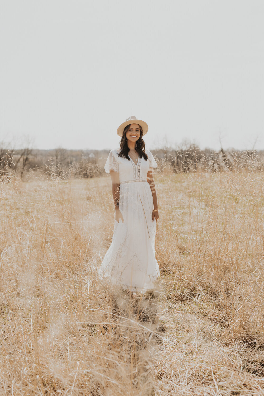 boho bride with lace dress and fedora in a field