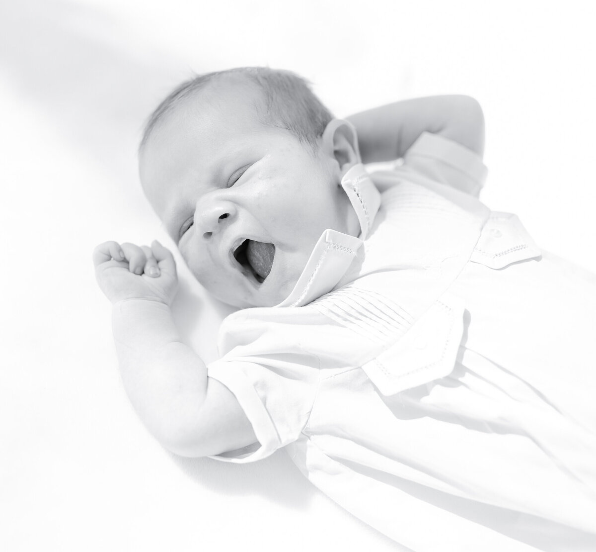 Newborn baby in white outfit, soft natural light, Birmingham newborn photographer – A peaceful newborn lying on a white blanket, gazing with curiosity, dressed in a delicate heirloom outfit.