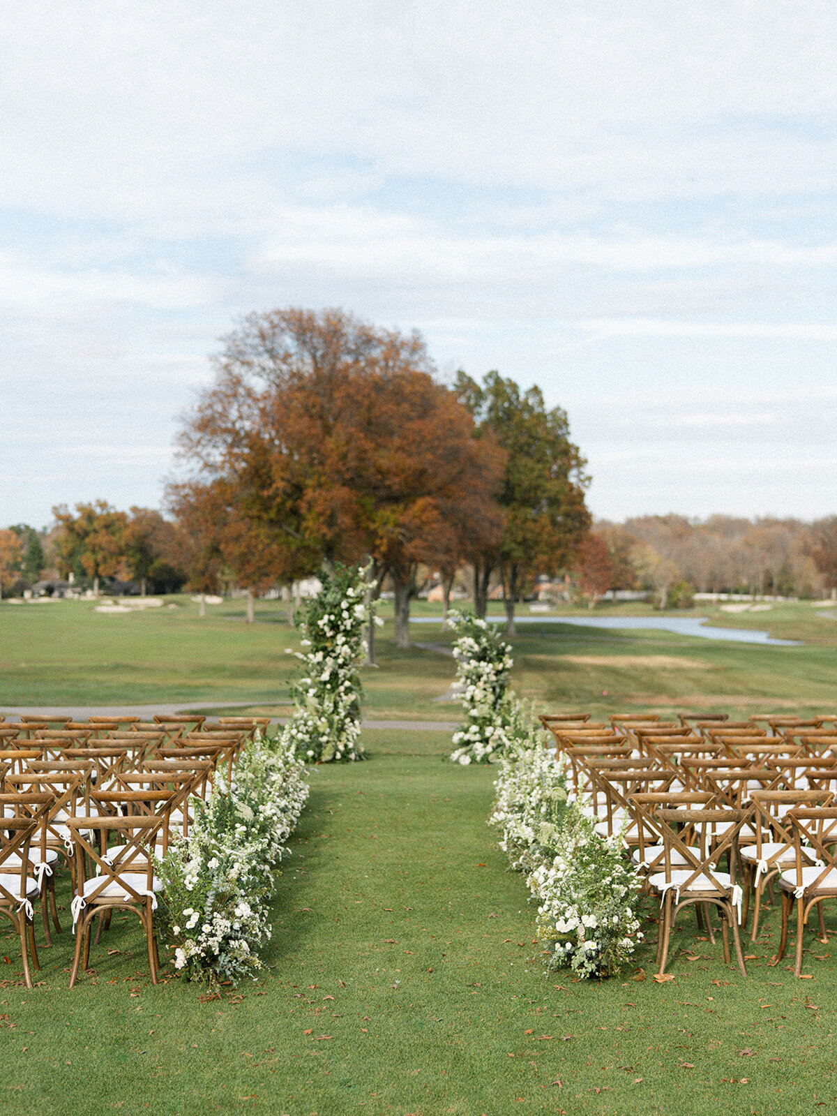 Lush green and white country wedding with meadow of aisle flowers and asymmetrical arch