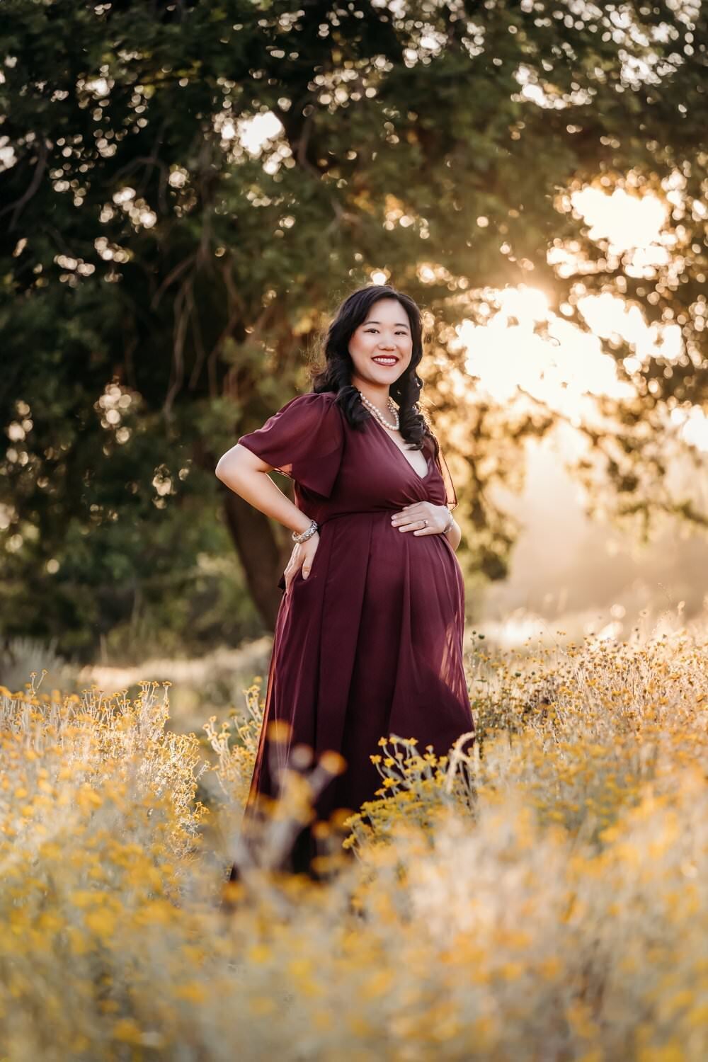 mom in red maternity dress smiling in pregnancy photo