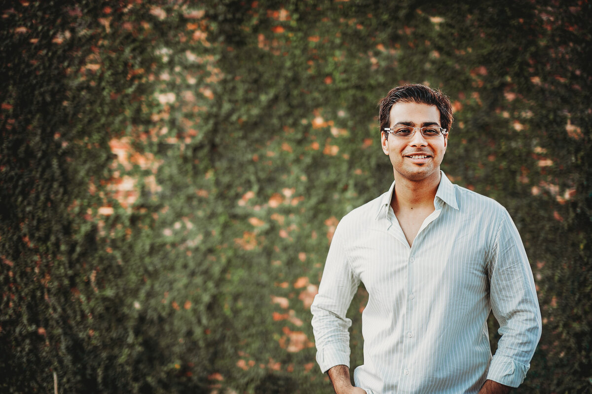 n smiling in front of a leafy ivy-covered wall during an outdoor portrait session in Winter Garden, Florida.