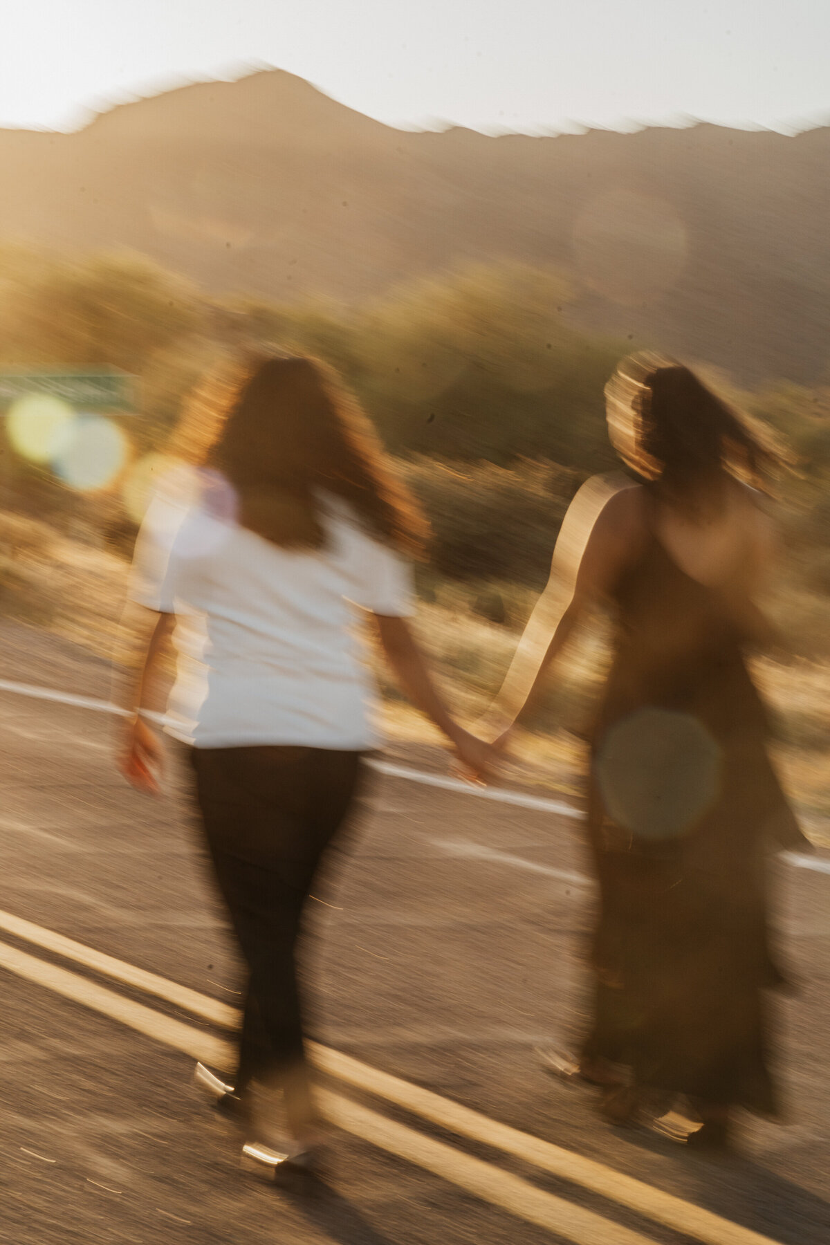 A blurred photo of a couple holding hands and walking along a road 