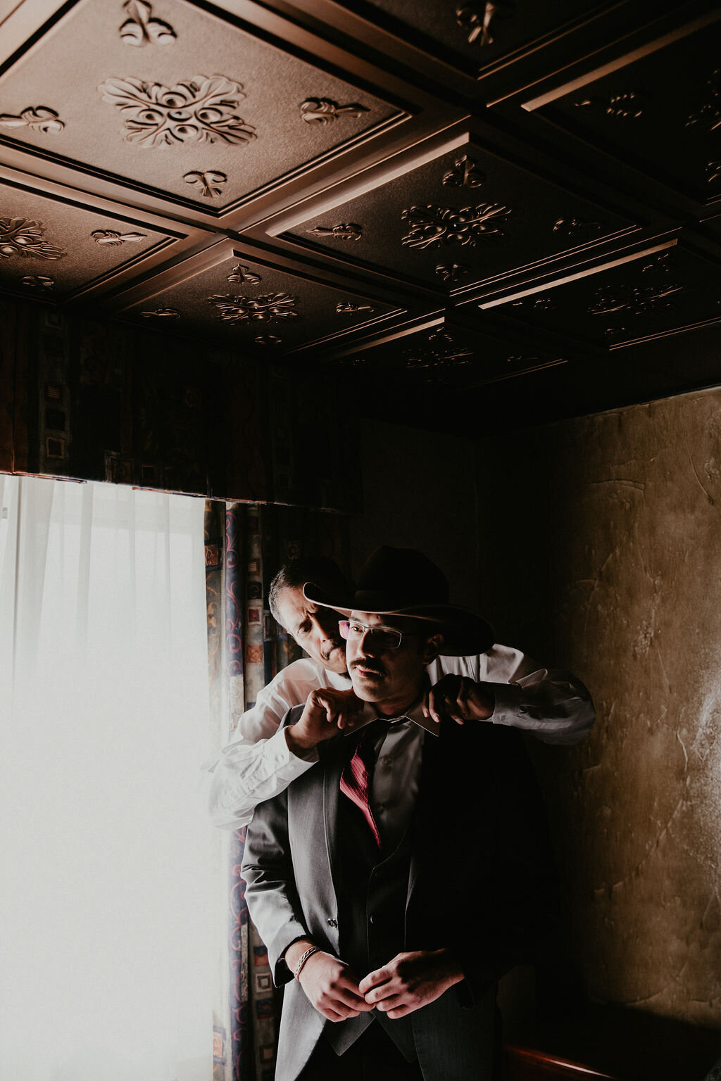 A groomsman helps the groom get ready