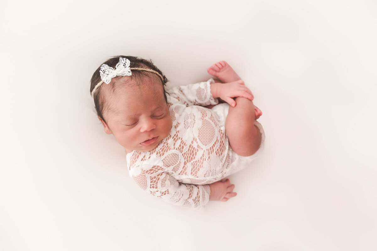 Baby newborn in lace outfit in womb pose, taken by Stickan Photography a Minneapolis Newborn Photographer