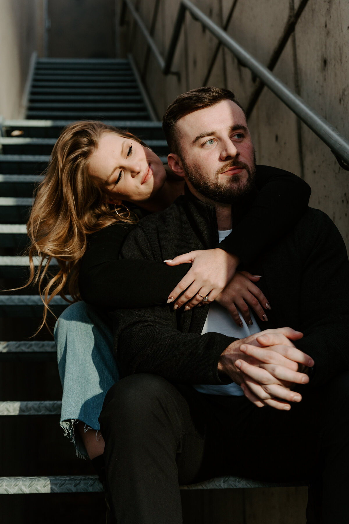 A couple sitting on a staircase with one's arms around the other's shoulders