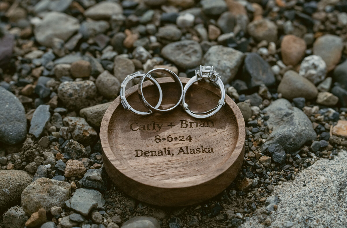 wedding rings on a wood ring tray in Alaska on stones