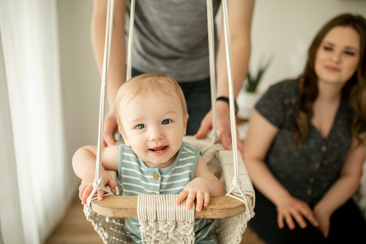 laughing baby in swing with parents watching