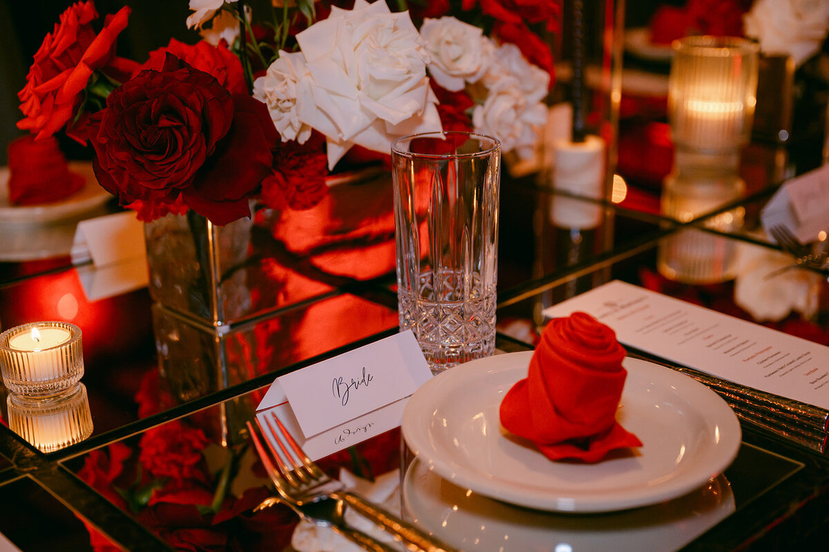 Cinematic tabletop styling featuring velvet rose napkin and mirrored dinner setting at The Battalion