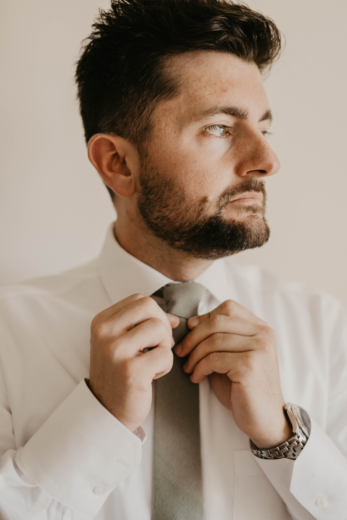 Groom straightening his tie.