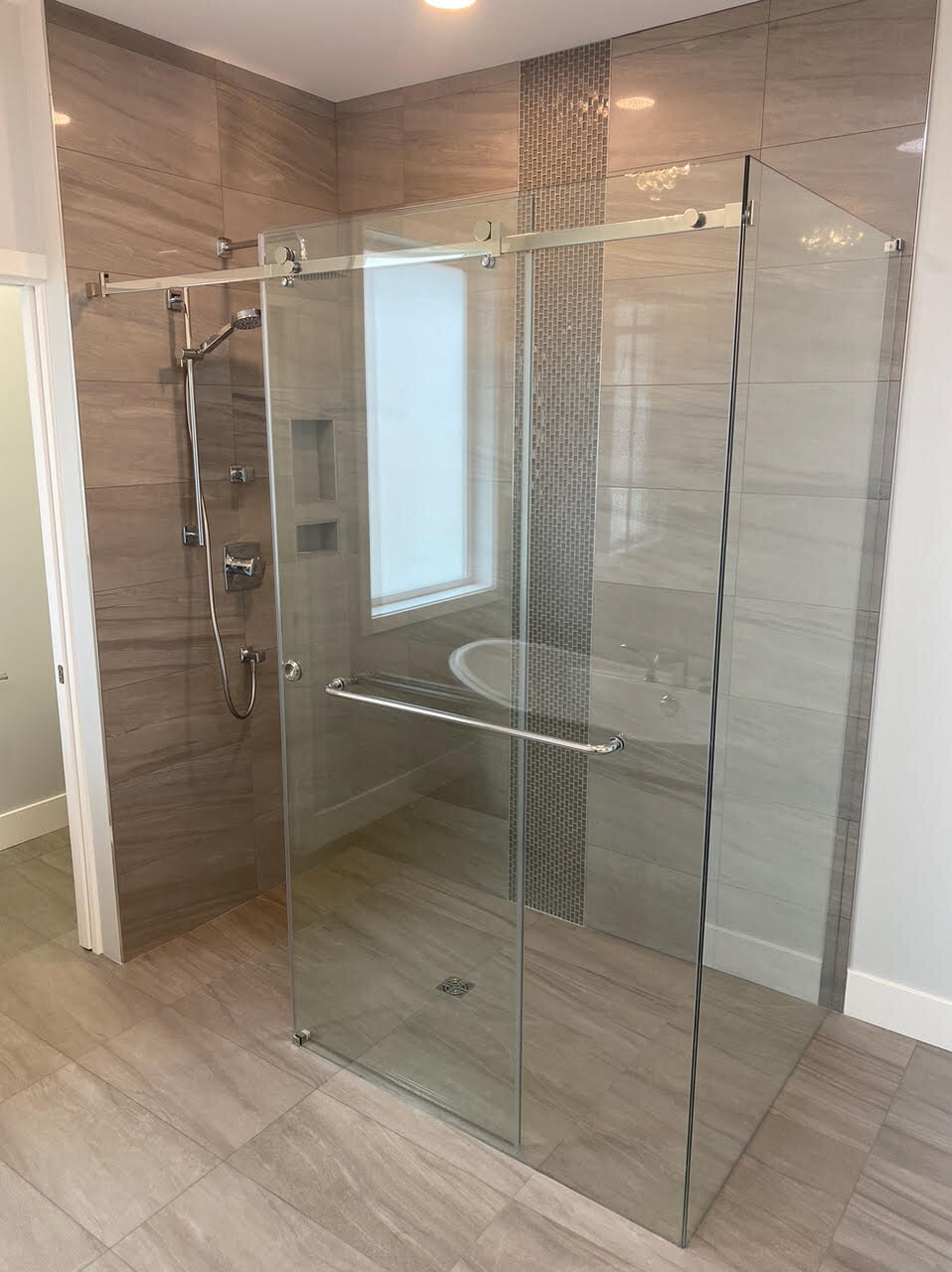 Ensuite shower design with accent tile, glass surround, and chrome fixtures by K2 Developments.