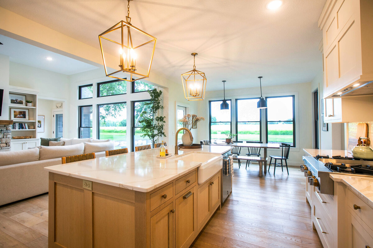 Open kitchen with white cabinets, large island, and quartz countertops in an Otsego custom home
