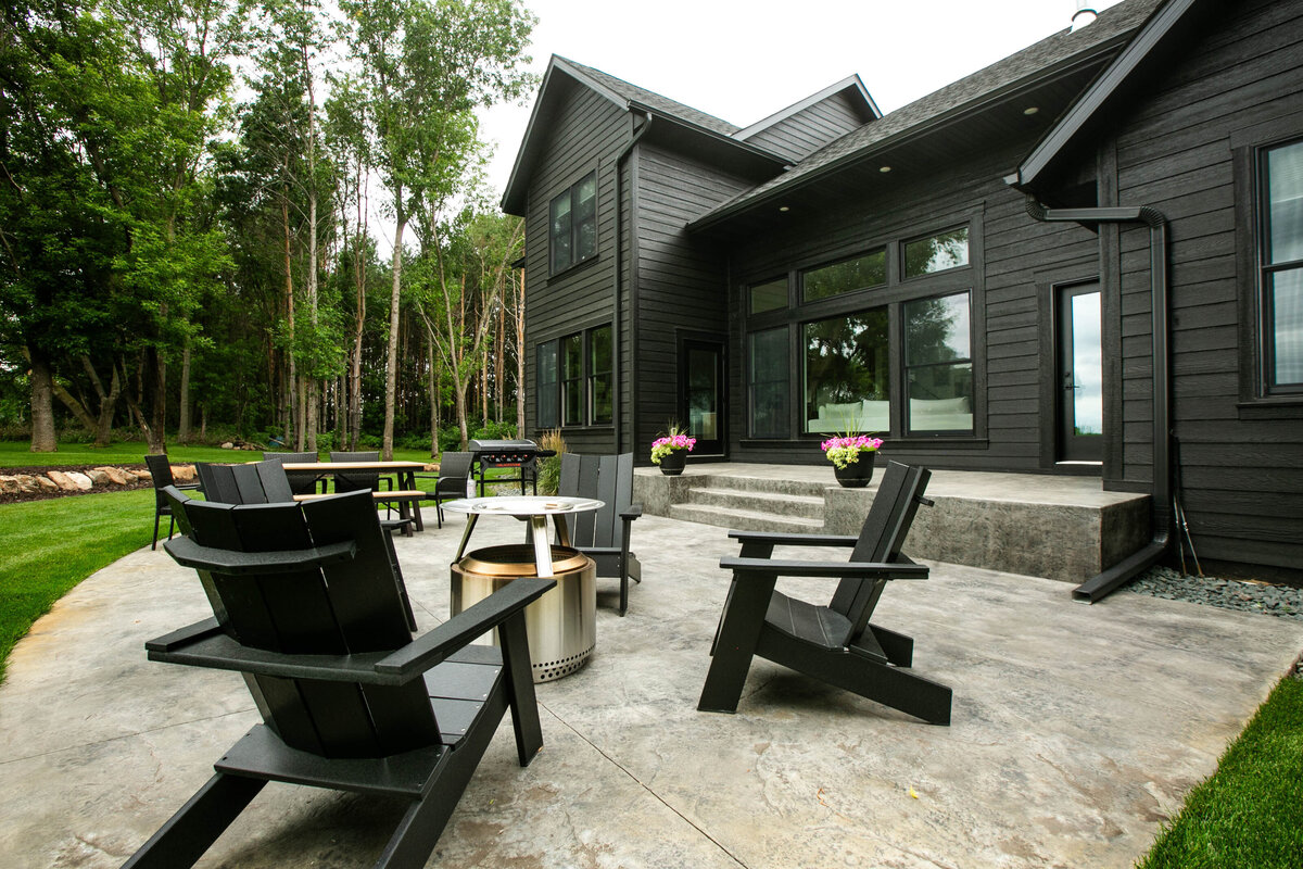 Exterior view of custom home in Otsego, Minnesota with black siding, large patio and windows built by Cornerstone Custom Builds