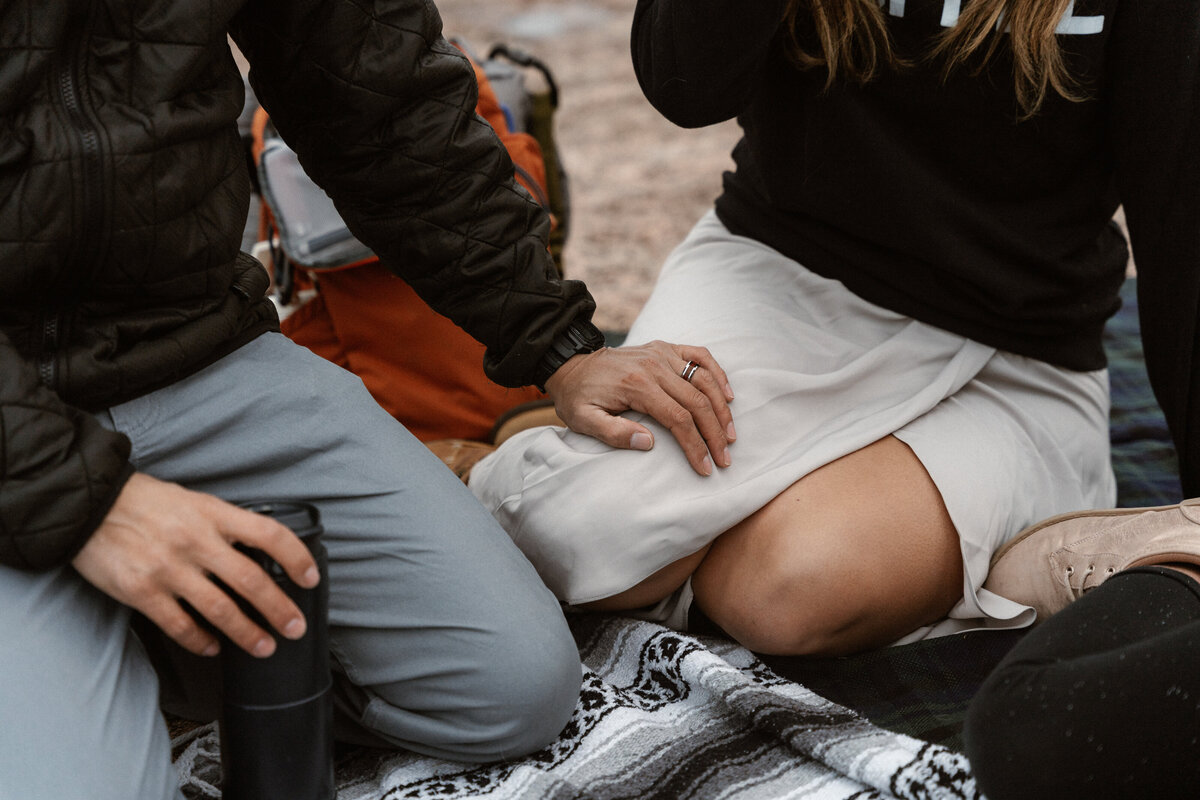 Groom rests hand on his bride's leg after hiking Enchanted Rock's Summit trail for their adventure elopement in Texas
