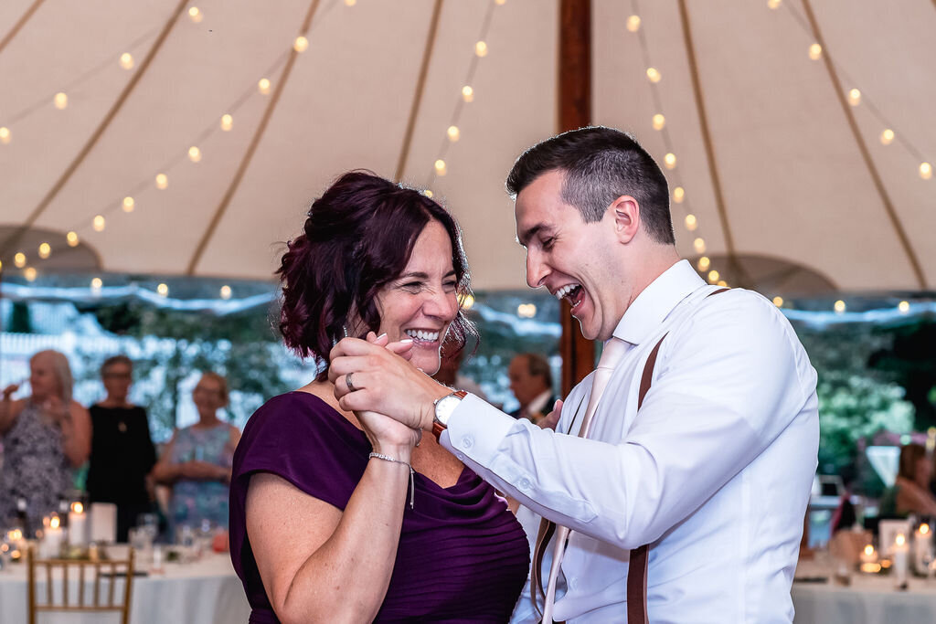 Joyful mother and son dance in tented reception at The Gardens at Uncanoonuc Mountain in Goffstown NH by Lisa Smith Photography