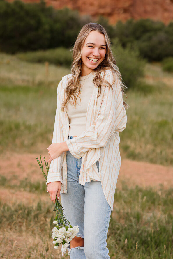 Girl holds arm and poses for her senior photo session at South Valley Park.