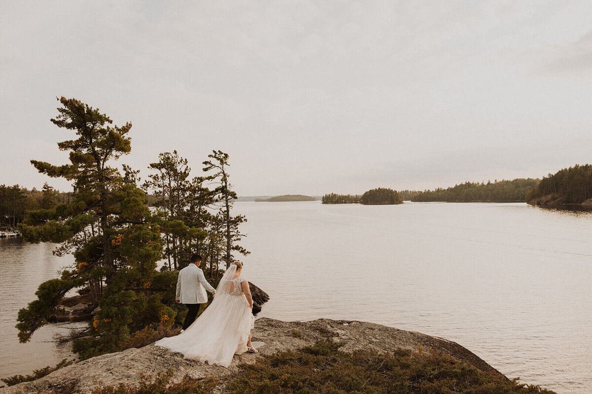 Bride and groom walk on cliff in North Shore of Minnesota