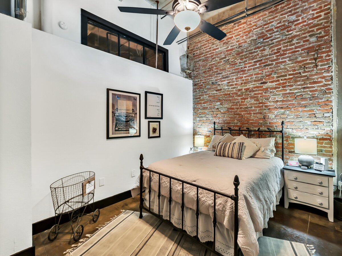 Spacious bedroom with beautiful bedding in this three-bedroom, two-bathroom industrial vacation rental loft with free WiFi, skyline view, and fully stocked kitchen in downtown Waco, Tx