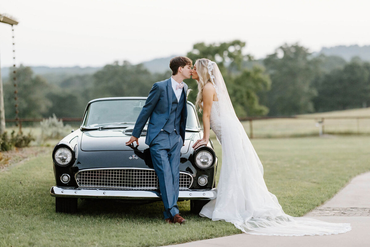 Texas wedding venues. Wedding day portraits of bride and groom leaning against vintage car at El Cerrito Lodge in Diana, Texas