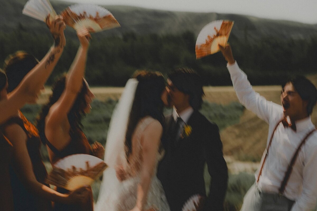Wedding Couple kissing while wedding party cheers them on in Drumheller, Alberta