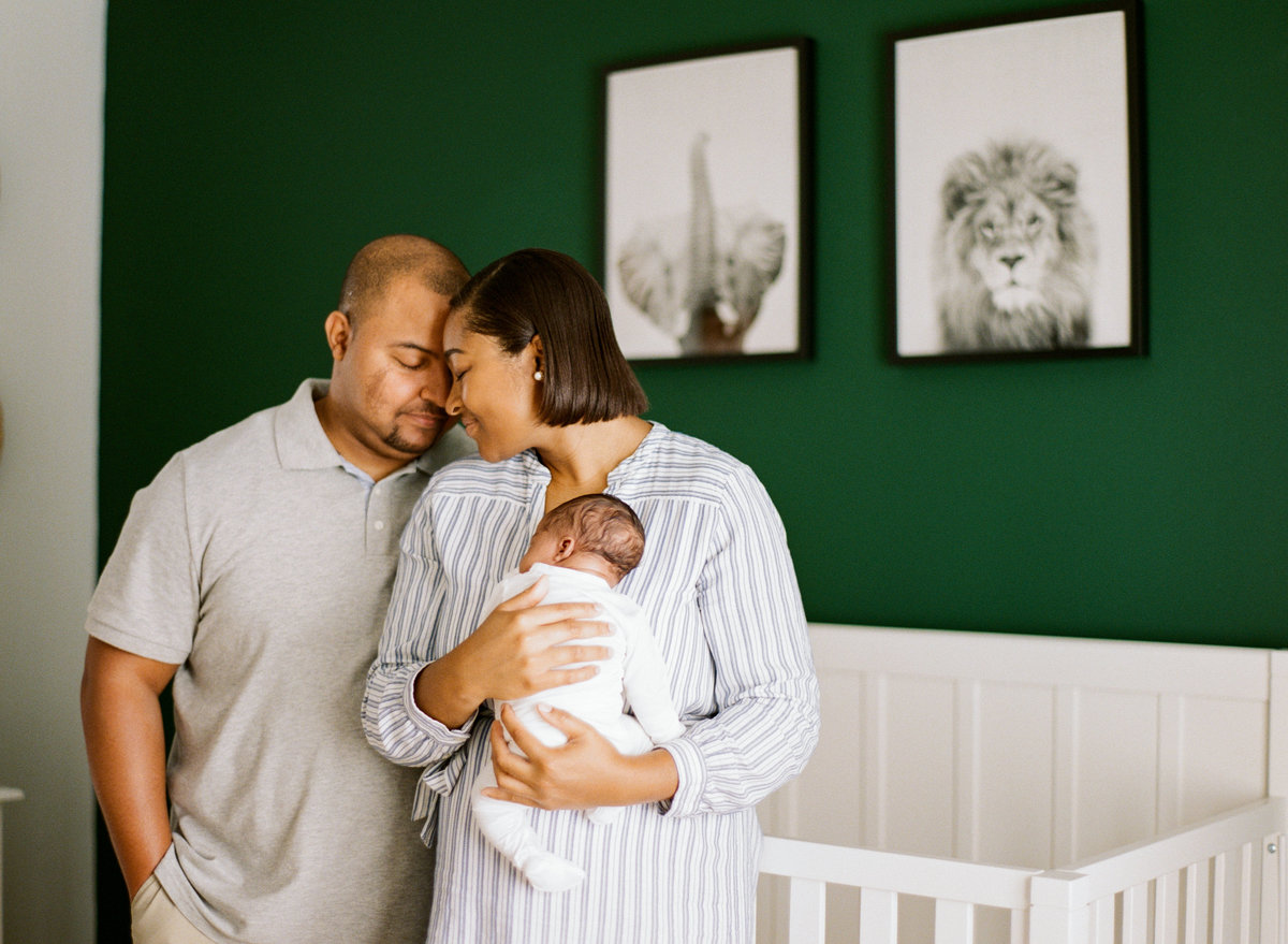 Dad and mom touching foreheads during a newborn session photographed in Raleigh. Photographed by newborn photographers Raleigh A.J. Dunlap Photography.