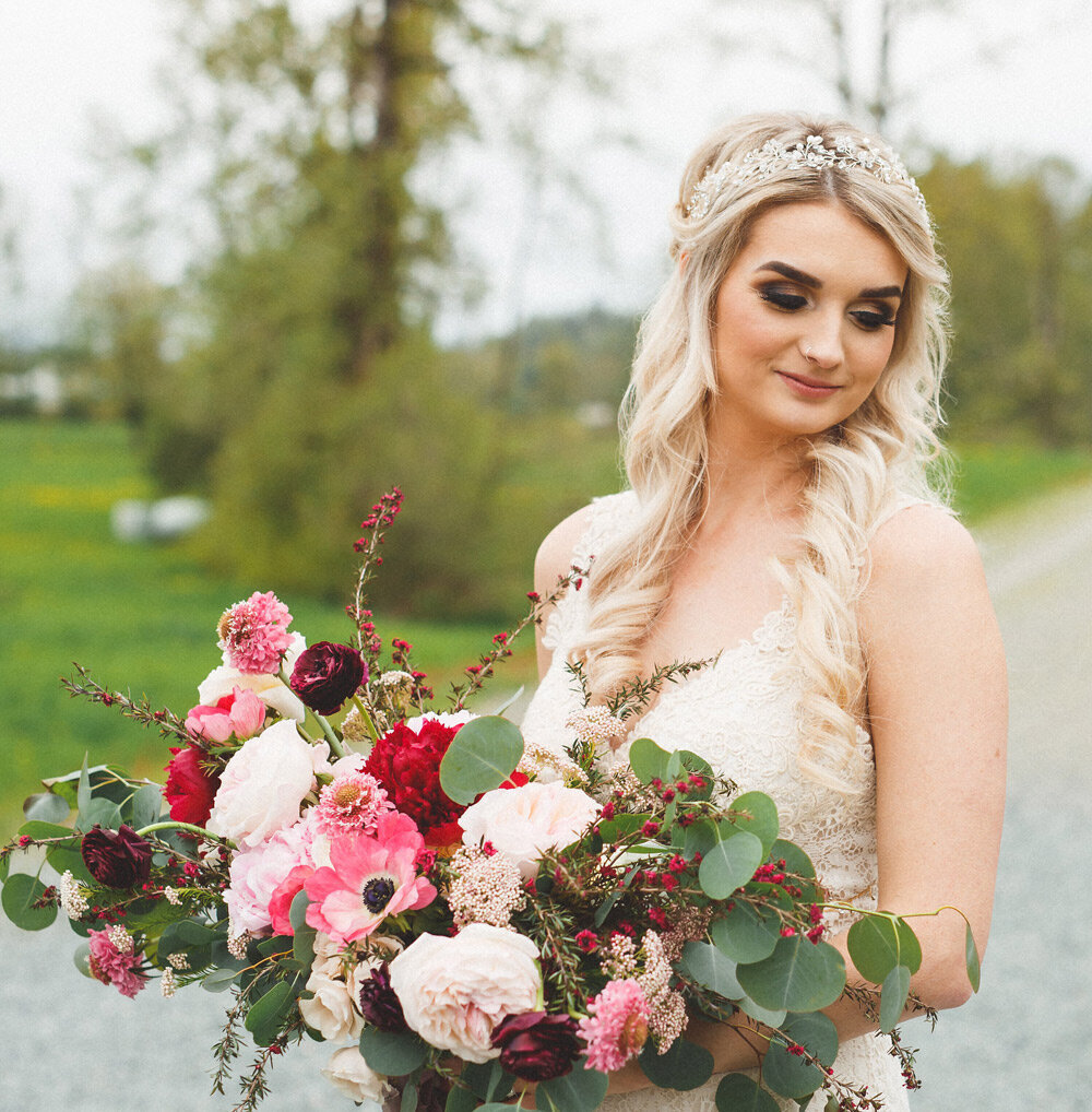 Blonde bride with half updo poses outdoors with bouquet