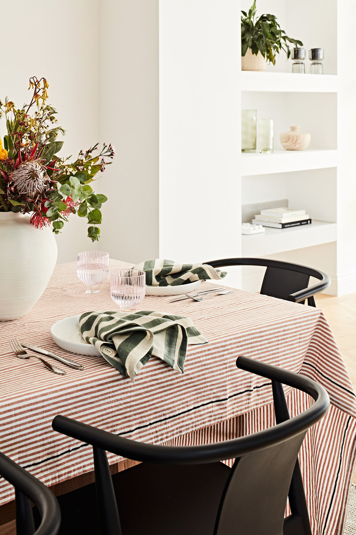 Hampton East dining table styled with striped cloth, flowers, and modern black chairs