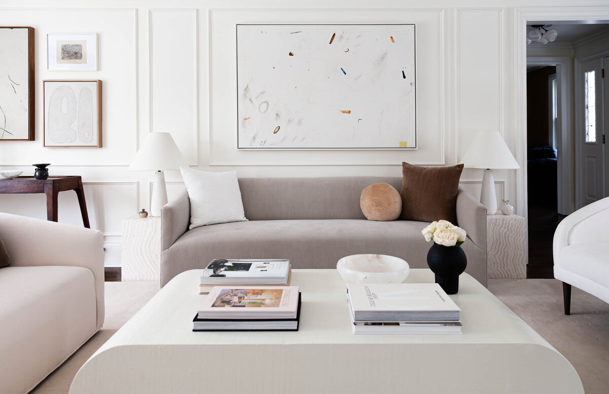 Elegant neutral-toned living room by Deni + Dove Interiors, a luxury interior designer serving Short Hills, Summit, Montclair, and Chatham, NJ—featuring minimalist furnishings, abstract art, and curated coffee table styling.