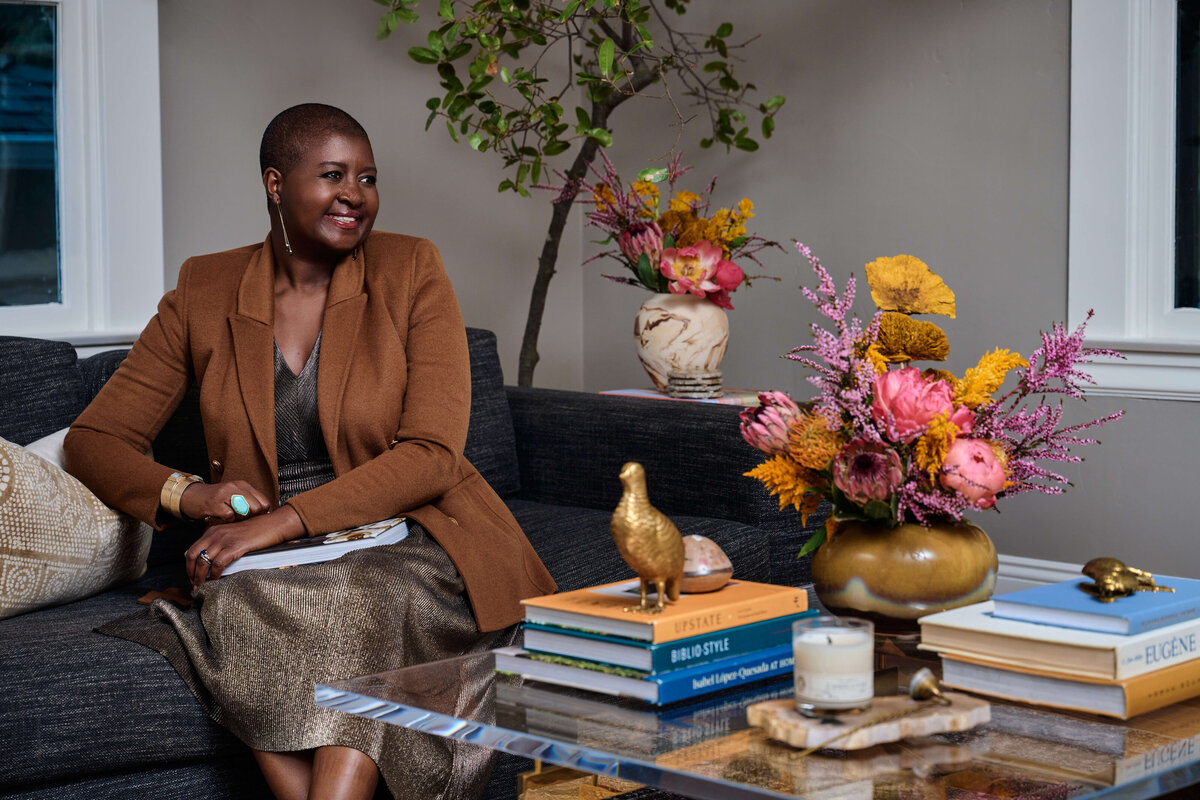 a woman in blue dress sitting in a chair reading a book