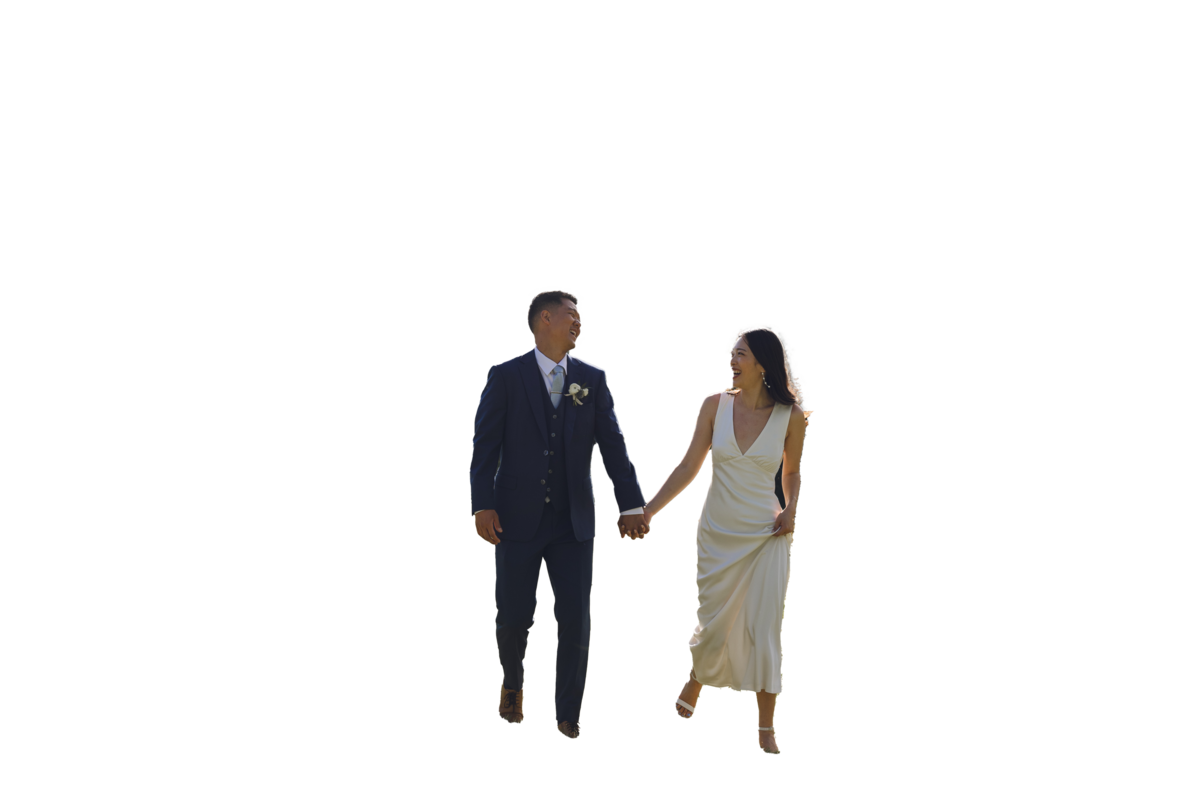 Bride and groom walking hand in hand through a sunny New Jersey field, laughing