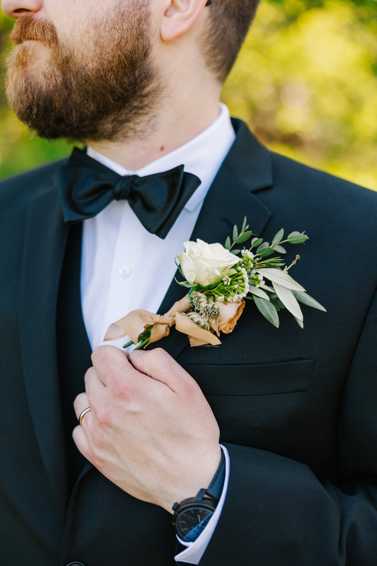 Close up photo of groom's boutonniere pinned on his jacket