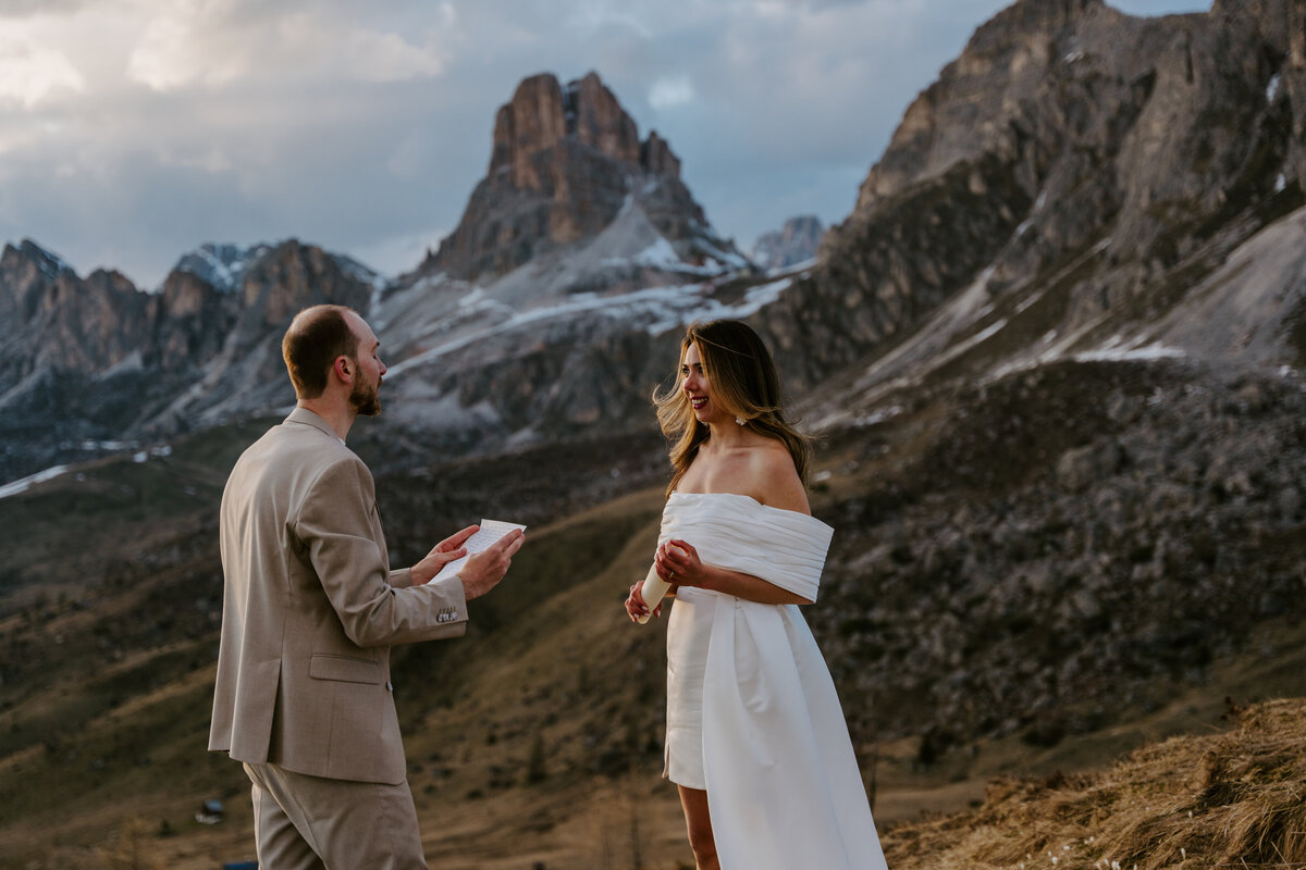 Groom reading vows to bride in Dolomites at golden hour