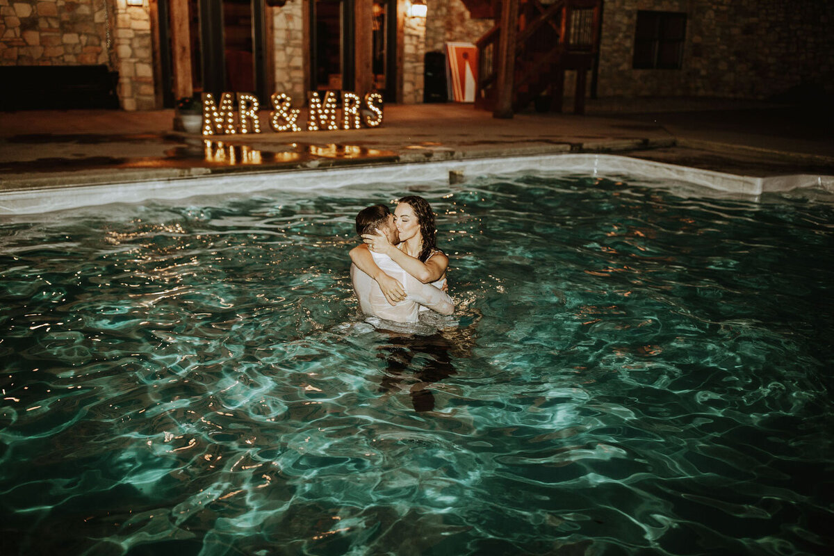 Couple embracing in a lit pool at night