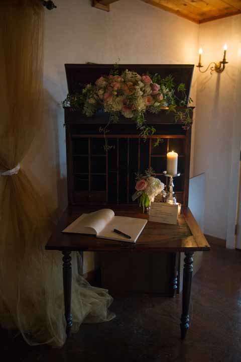 welcome table with vintage wooden table, candle, and floral arrangement