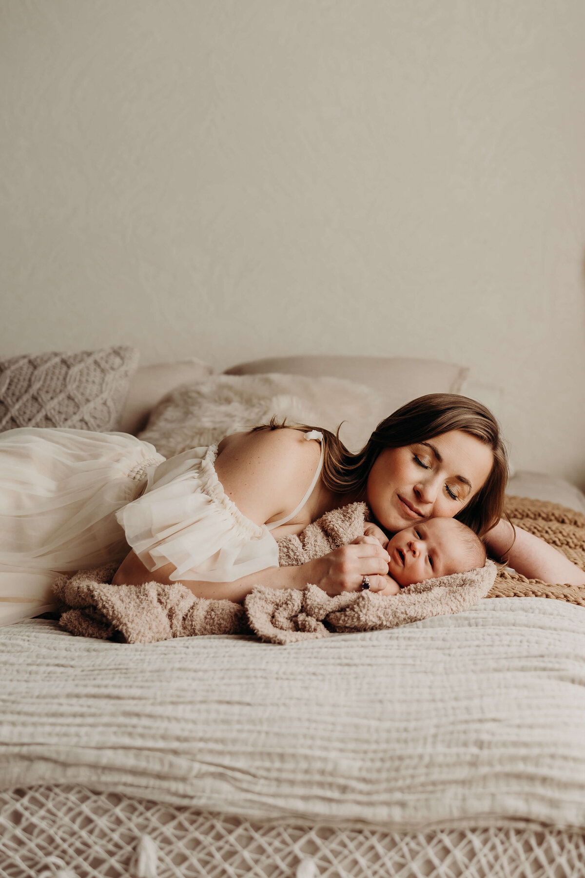 fine art style portrait of mother with her newborn son laying on a bed