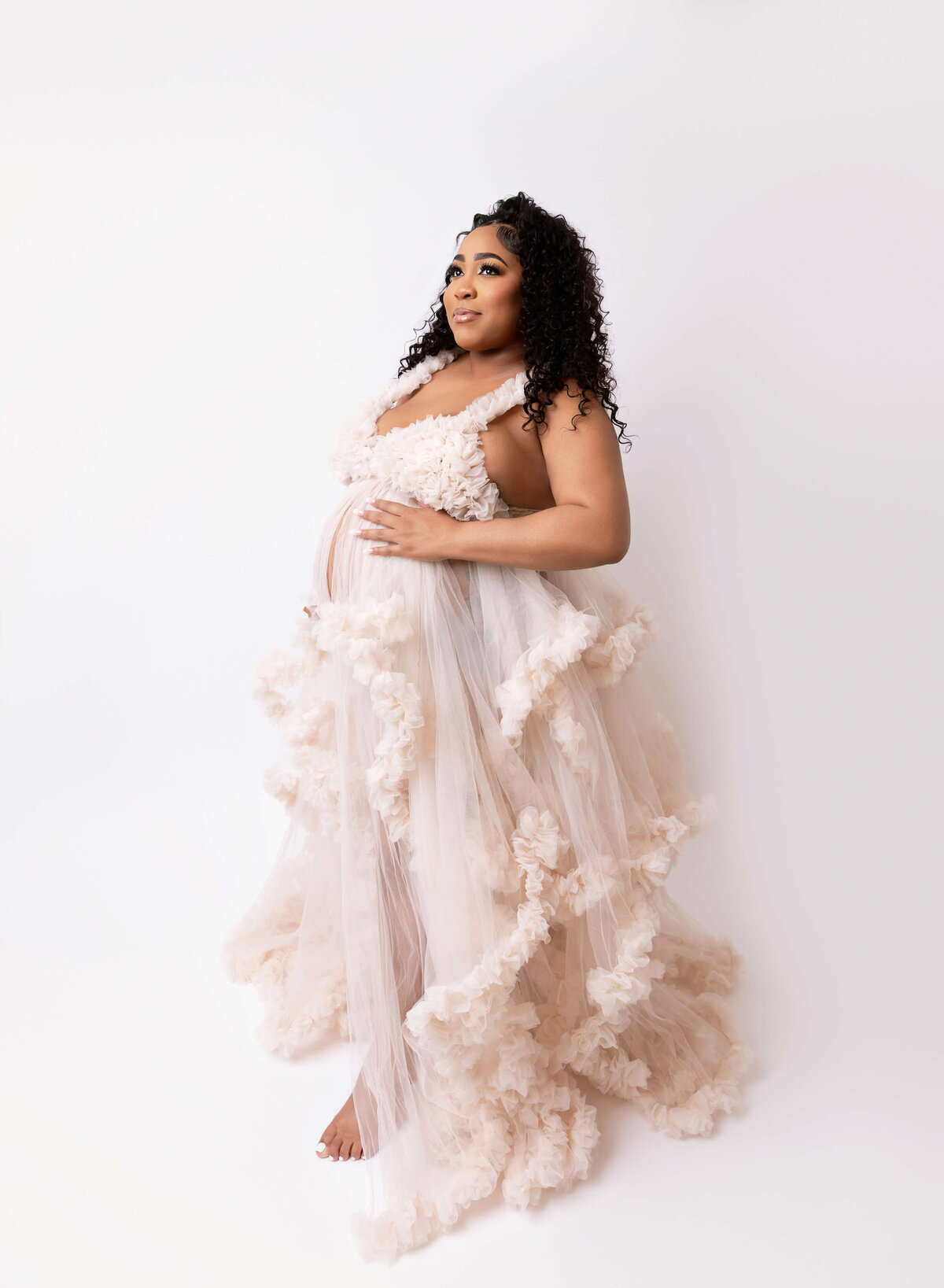 Expectant mother in an ivory dress, beautifully captured during a maternity photoshoot in NYC, showcasing the elegance and joy of pregnancy
