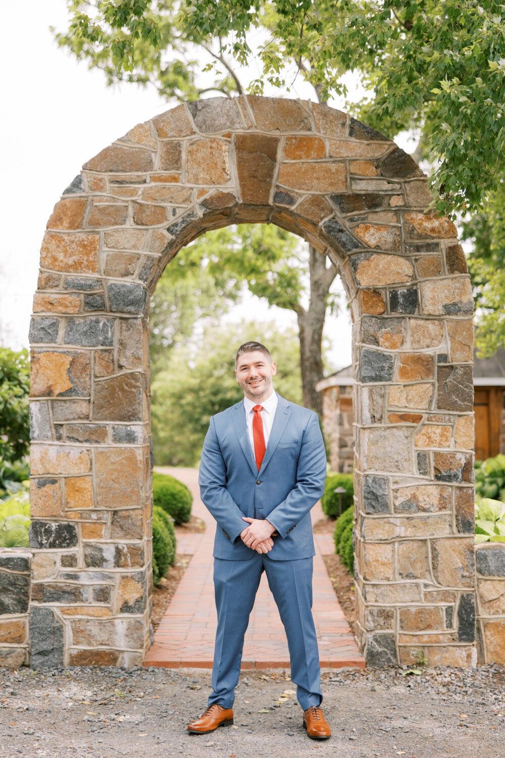 Groom standing in a stonewall arch