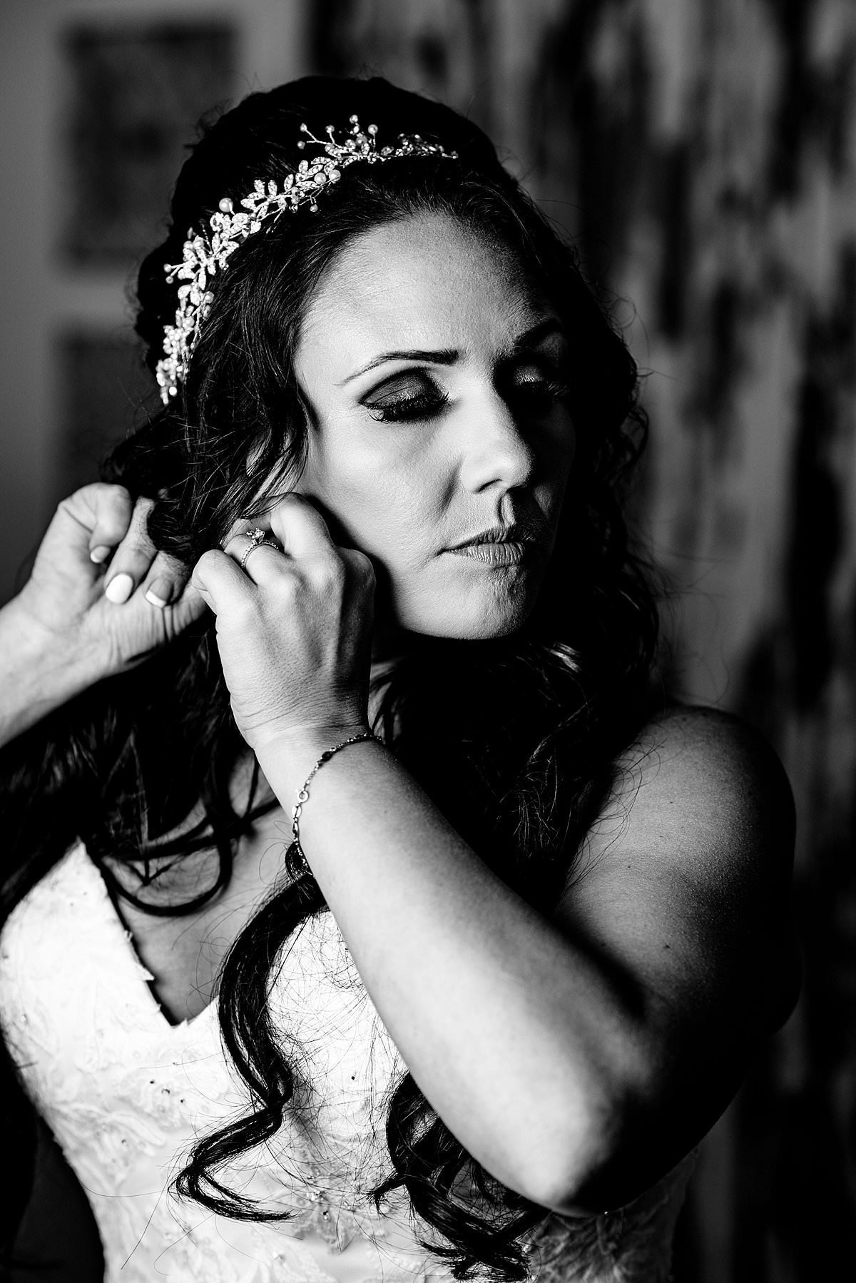 Black and White portrait of bride putting earrings on