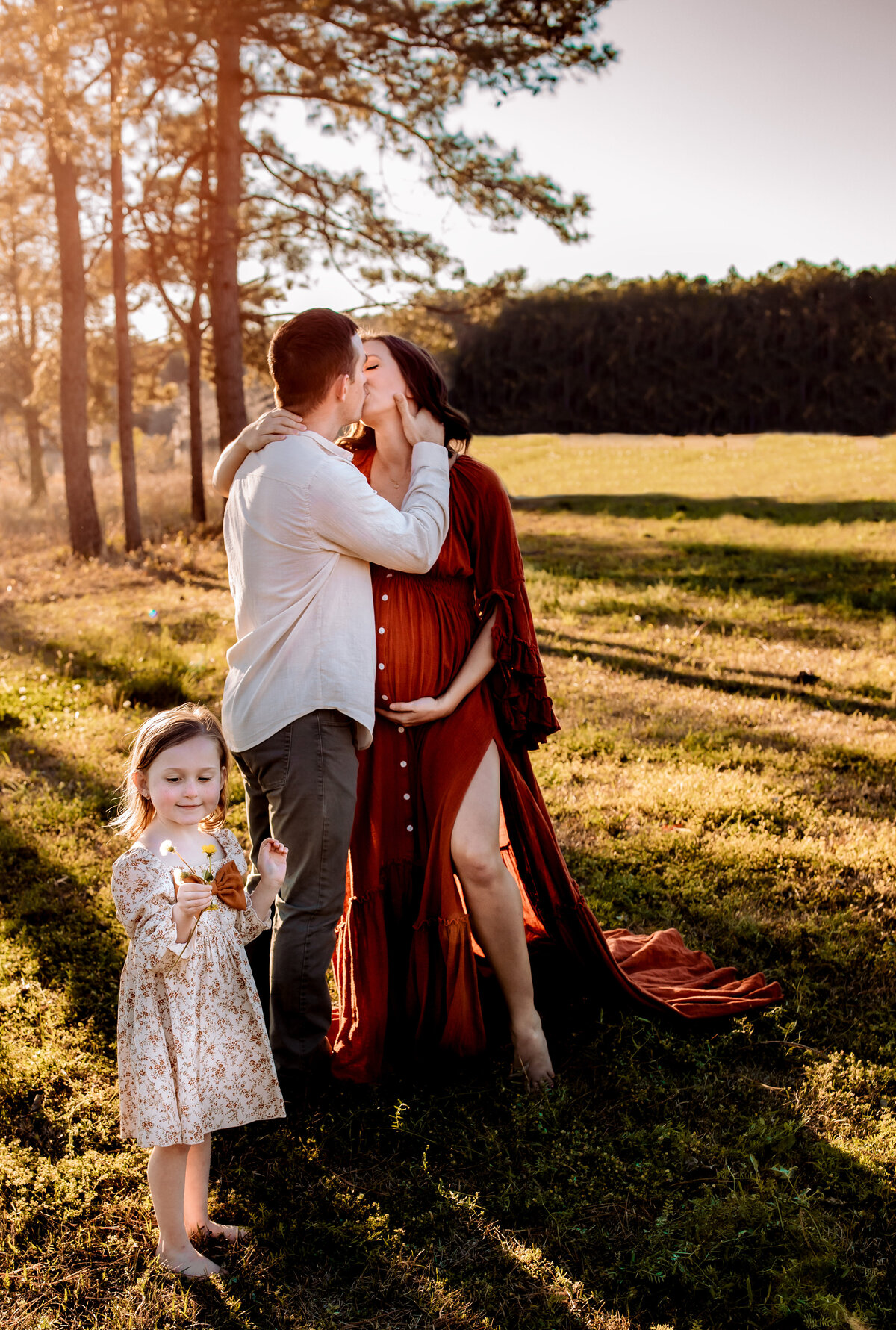 mom and dad kissing behind ing, daughter  looking at the wild flowers in Perrysburg